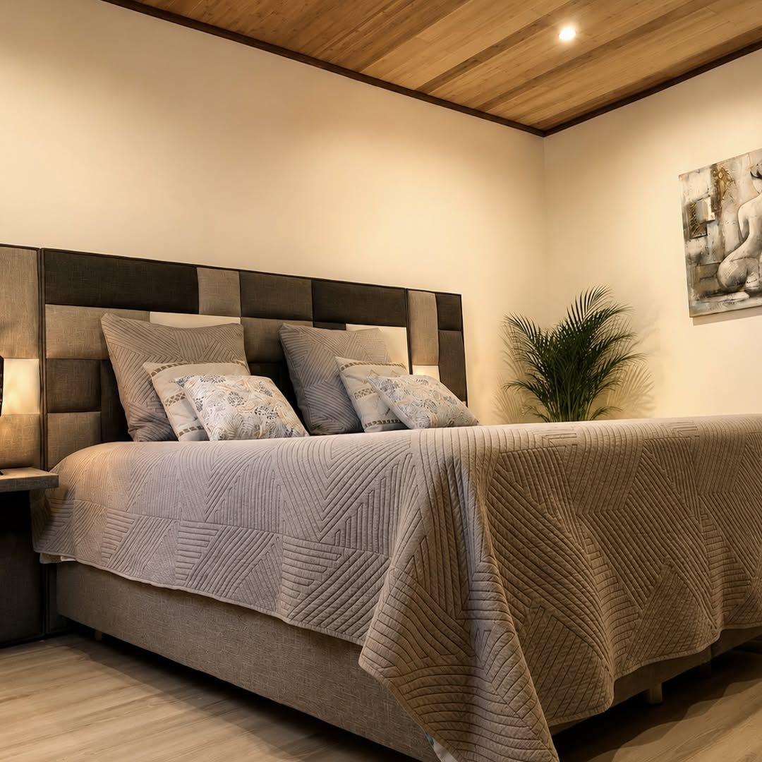 Chambre avec grand lit, tête de lit capitonnée et plante